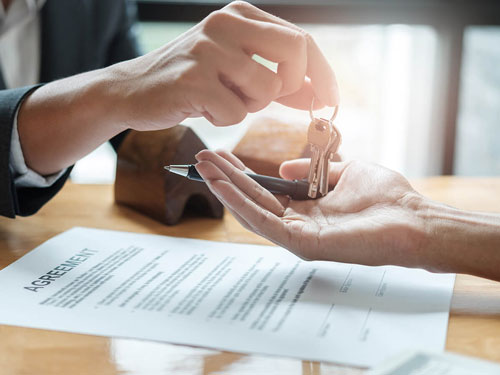 Person in a suit handing keys to another person's hand