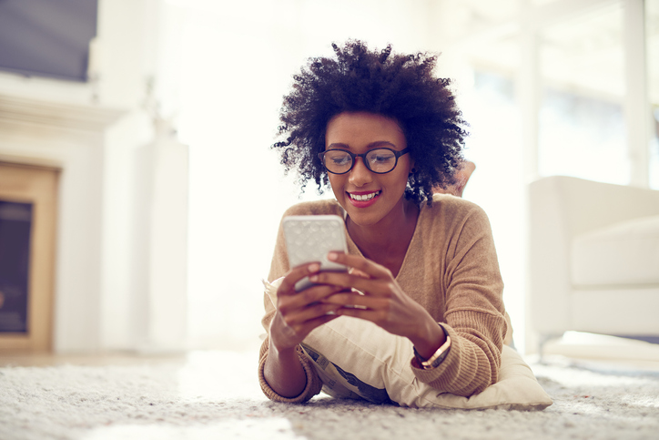 Person laying on the floor looking at their title on the phone through an app